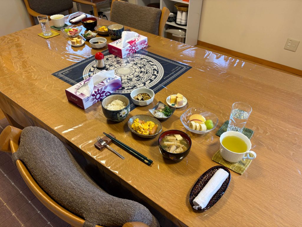 Table set for a meal with many small bowls of food, tissue box, and cups viewed from above in a cozy dining room.