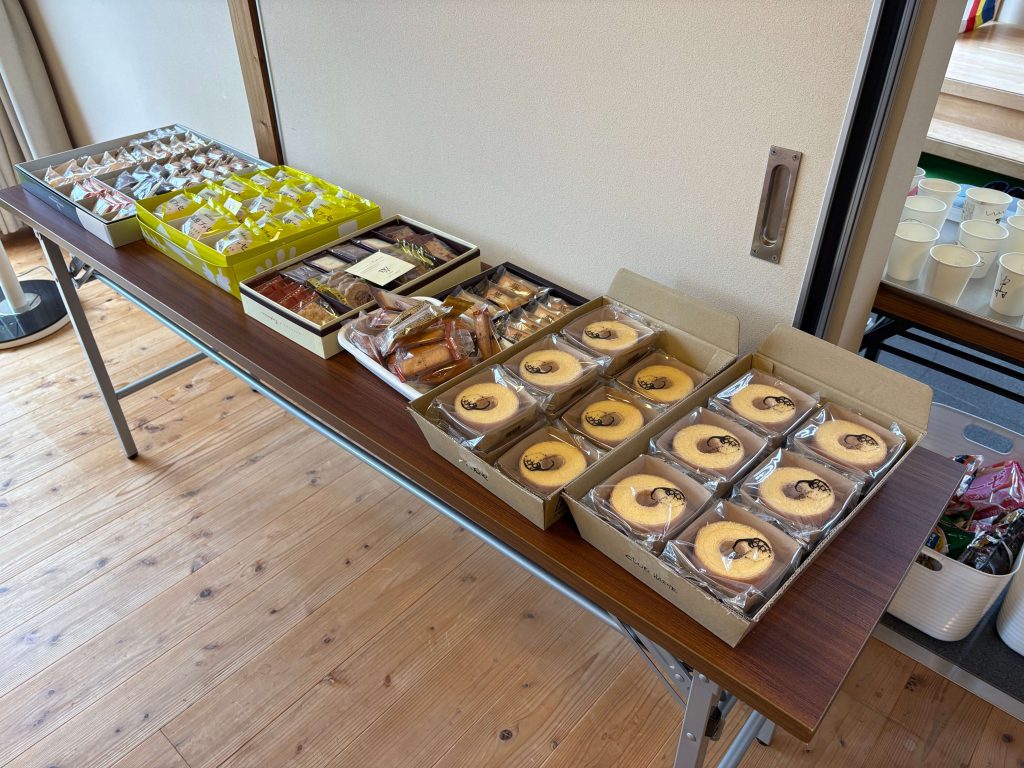 Assorted packaged pastries arranged in open boxes on a wooden table in a bright room.