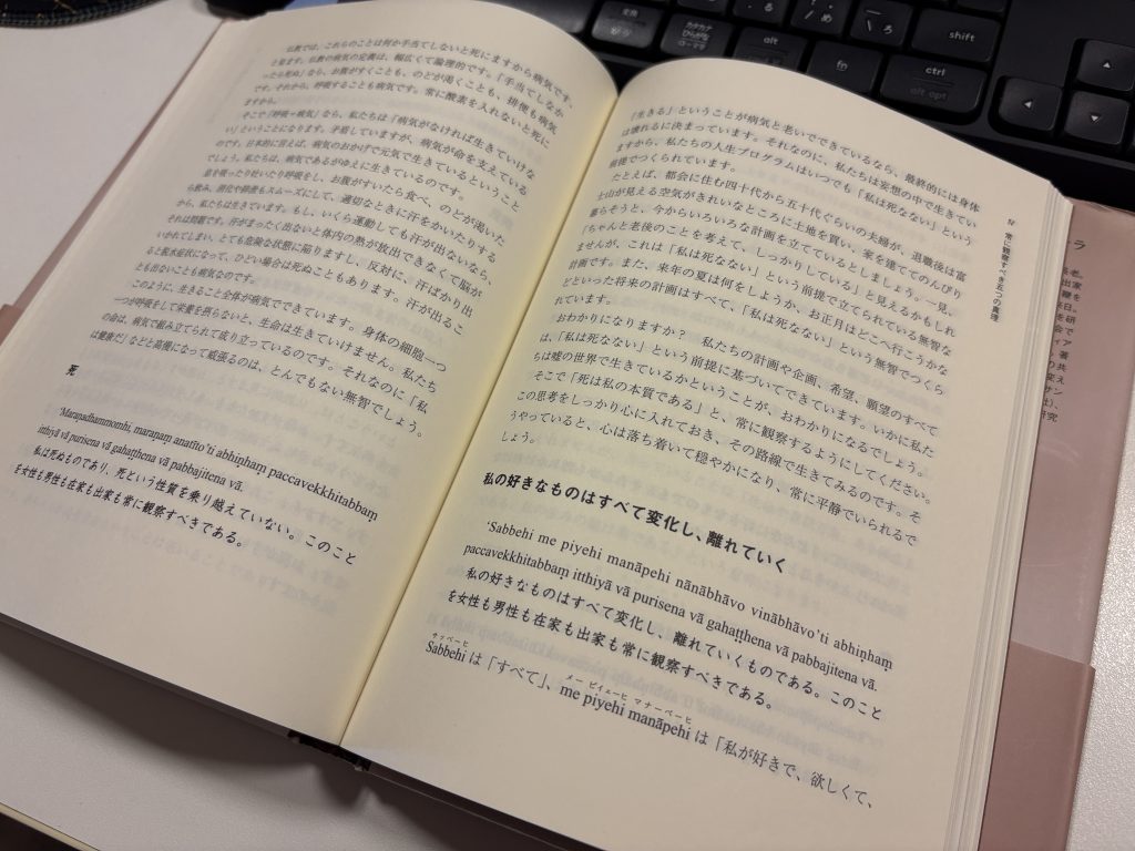 Open book with Japanese text on a desk; a computer keyboard visible in the background.